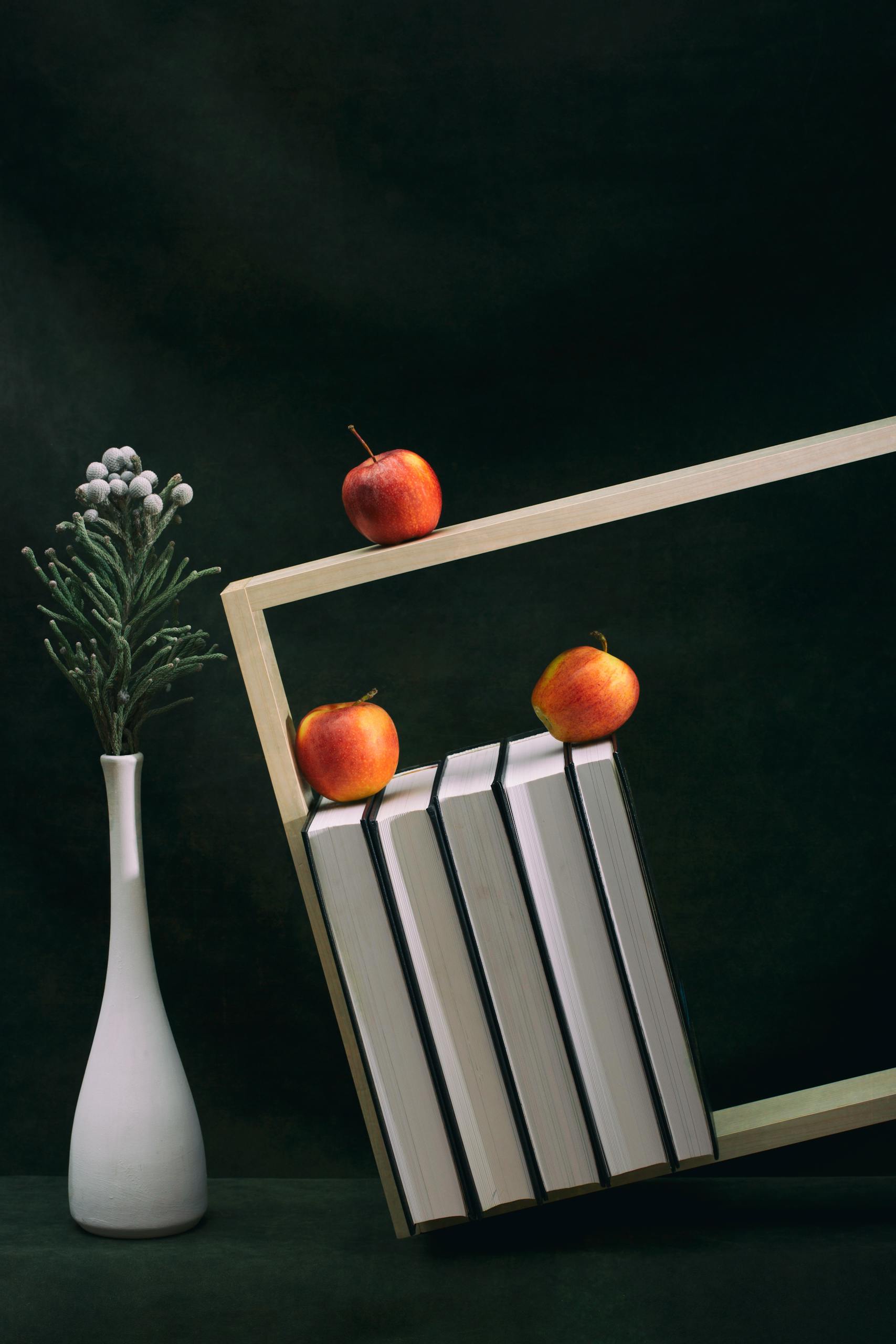 A creative still life featuring apples, books, and a vase for an artistic touch.