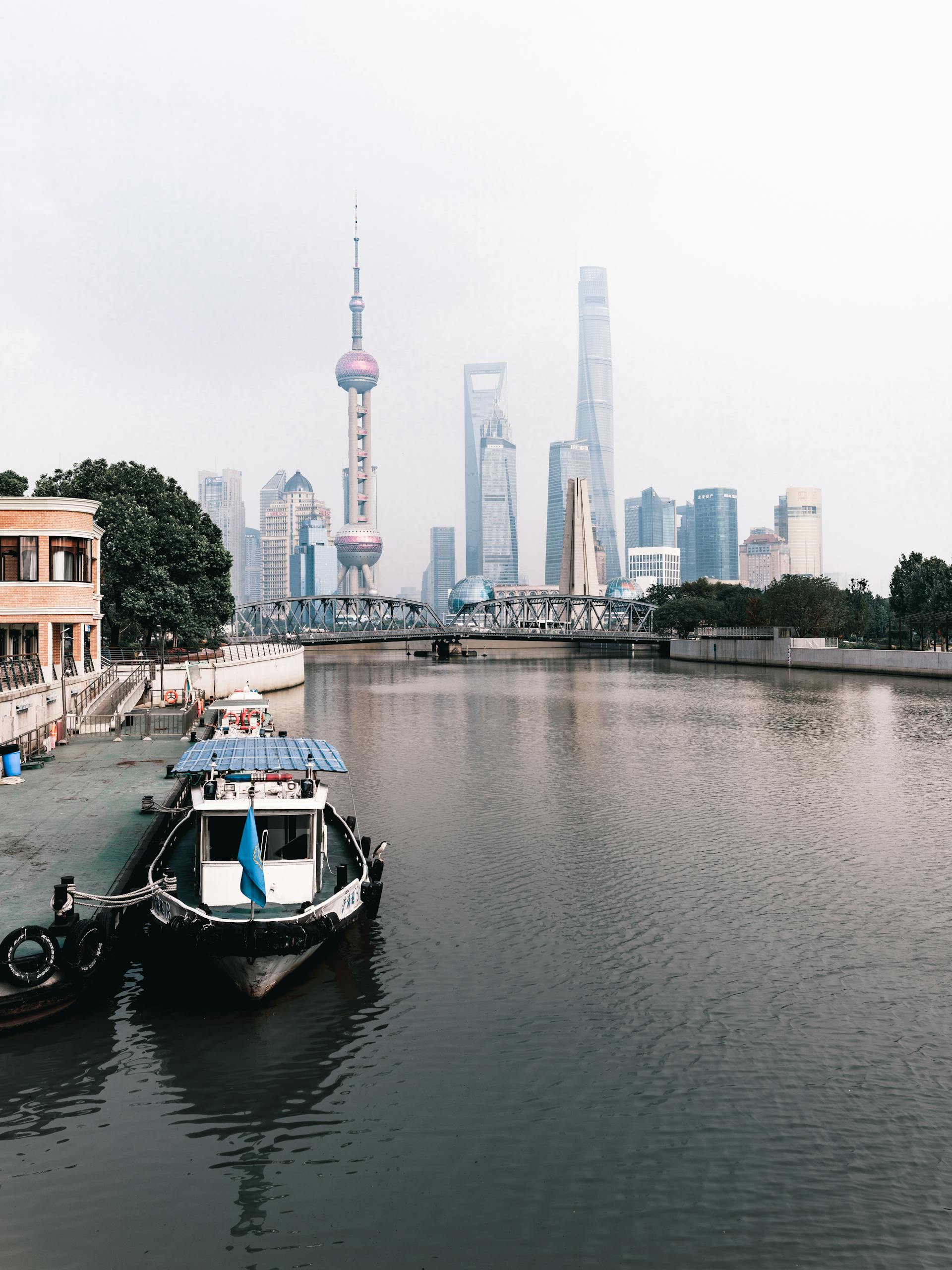 A motorboat docked by the Huangpu River with Shanghai's iconic skyline in the background.