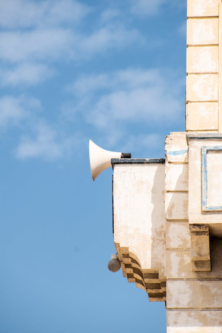 Megaphone on a vintage building corner set against a blue sky background.