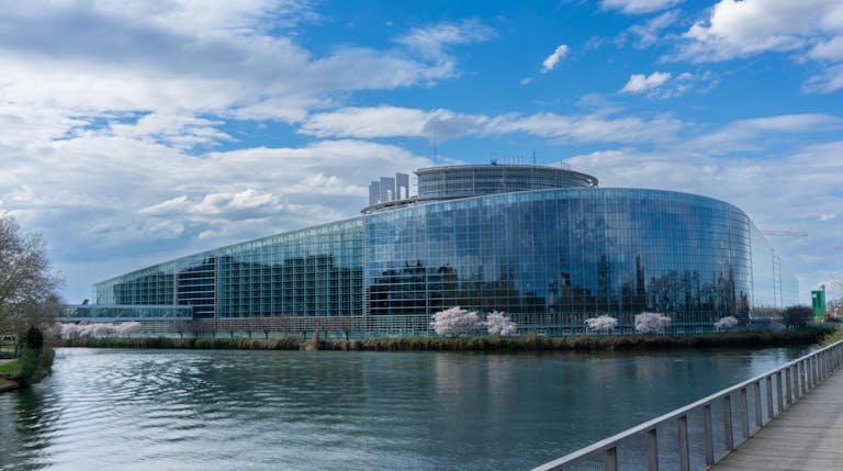Modern architecture of the European Parliament building in Strasbourg with a reflective glass facade and river view.