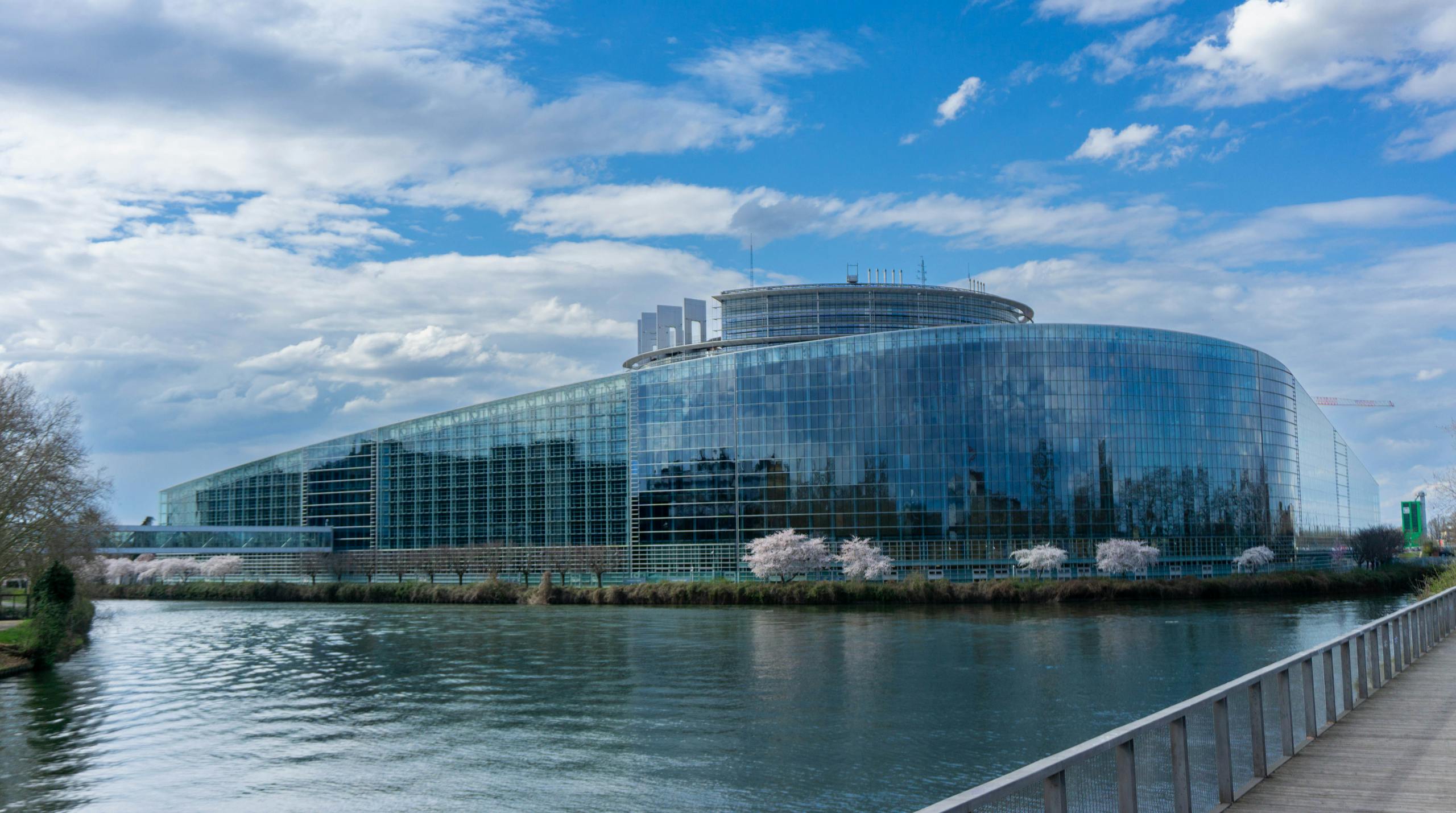 Modern architecture of the European Parliament building in Strasbourg with a reflective glass facade and river view.