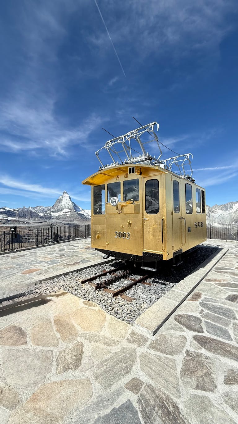 Vintage yellow train car at Gornergrat with the Matterhorn in view.